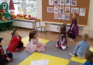 Widok na dzieci siedzące przed tablicą z bajkowymi postaciami. Amelka pokazuje obrazek z bajki o Kopciuszku.